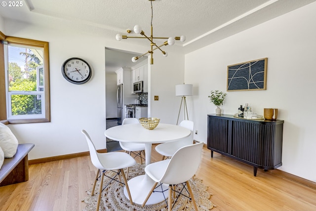 6220 SW 45th Ave, Portland, OR 97221 - dining area featuring light wood-style floors, a chandelier, a textured ceiling, and baseboards