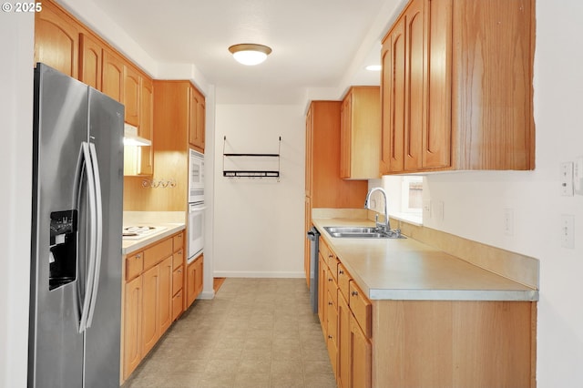 kitchen with baseboards, light floors, light countertops, stainless steel appliances, and a sink