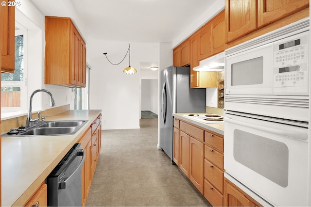 kitchen with under cabinet range hood, light floors, light countertops, appliances with stainless steel finishes, and a sink