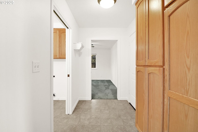 hallway featuring baseboards and light floors