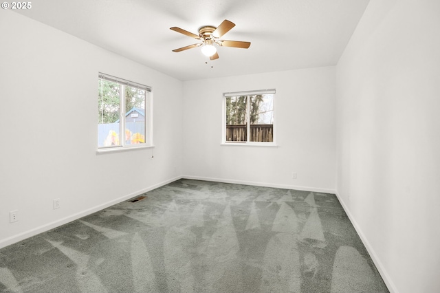 empty room featuring a ceiling fan, visible vents, carpet floors, and baseboards