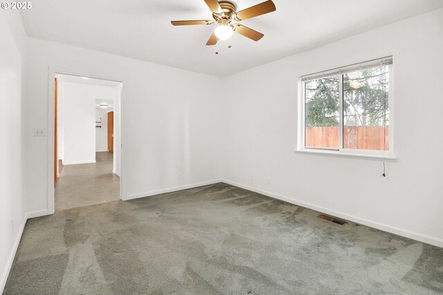 carpeted empty room with baseboards, visible vents, and ceiling fan