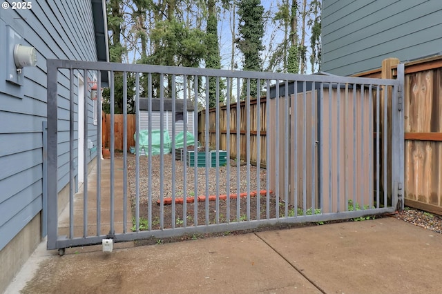 view of gate featuring a storage unit, an outdoor structure, and a fenced backyard