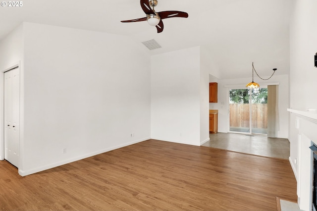 unfurnished living room with a ceiling fan, baseboards, lofted ceiling, a fireplace with flush hearth, and light wood-style floors