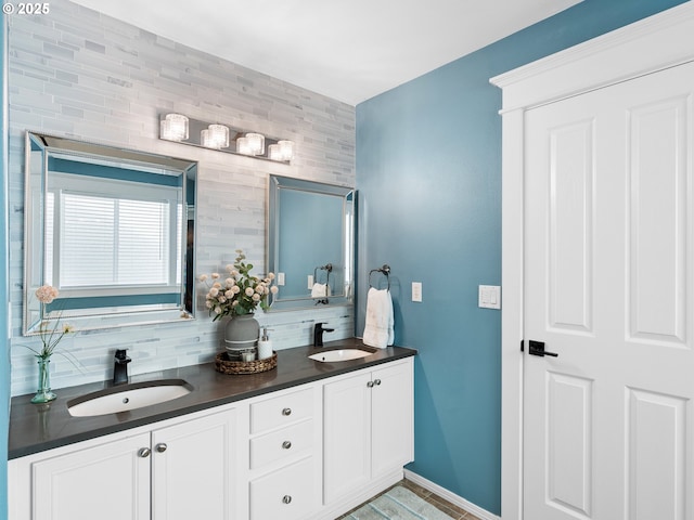 bathroom with double vanity, tasteful backsplash, a sink, and baseboards