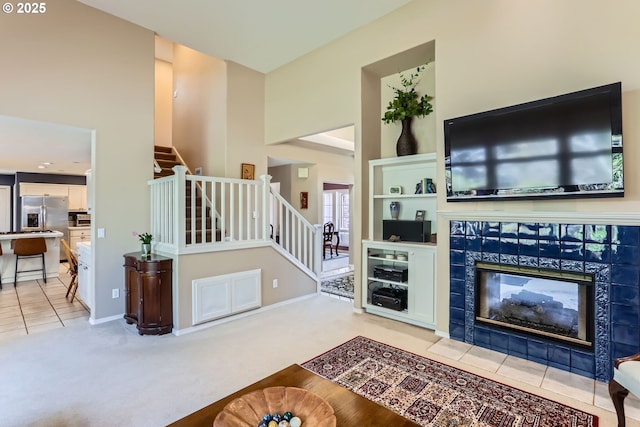8650 SW Turquoise Loop, Beaverton, OR 97007 - living room featuring stairs, a towering ceiling, a tile fireplace, light carpet, and light tile patterned floors