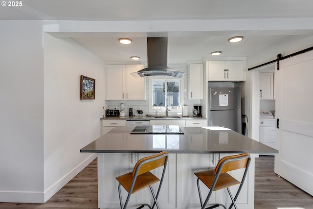 kitchen featuring stainless steel refrigerator, island range hood, a barn door, and a kitchen island