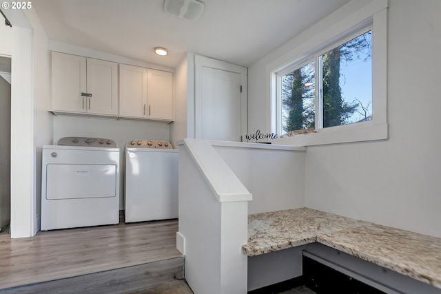 washroom with light hardwood / wood-style flooring, cabinets, and washing machine and clothes dryer