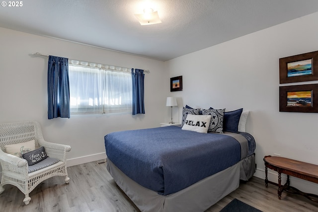 bedroom with a textured ceiling and light hardwood / wood-style flooring