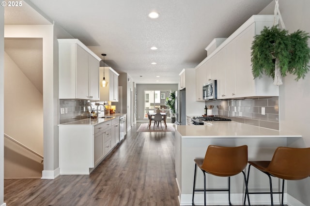 kitchen with stainless steel appliances, a sink, a textured ceiling, recessed lighting, and light countertops