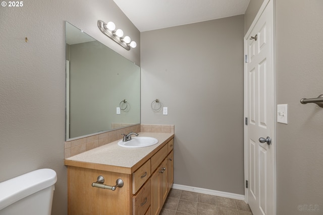 bathroom with decorative backsplash, tile patterned flooring, vanity, baseboards, and toilet