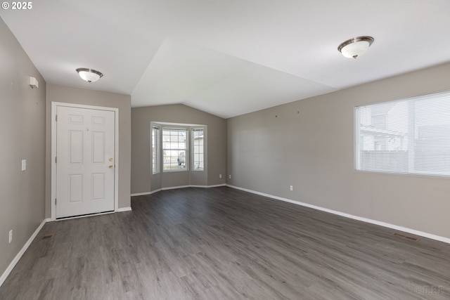 empty room featuring baseboards, visible vents, wood finished floors, and lofted ceiling