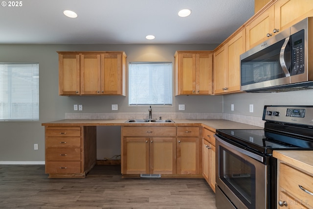 kitchen featuring appliances with stainless steel finishes, a sink, light countertops, recessed lighting, and wood finished floors