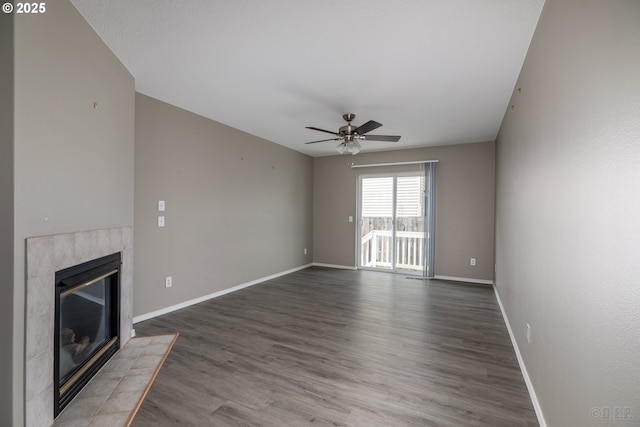unfurnished living room featuring baseboards, ceiling fan, a tiled fireplace, and wood finished floors