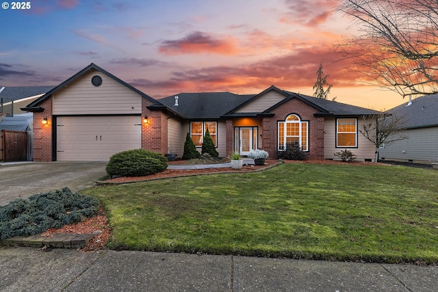 single story home featuring a garage and a lawn