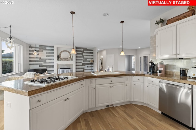 kitchen featuring sink, dishwasher, tasteful backsplash, white gas stovetop, and white cabinets