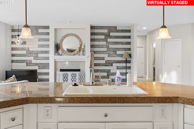 kitchen with hanging light fixtures, sink, and white cabinets