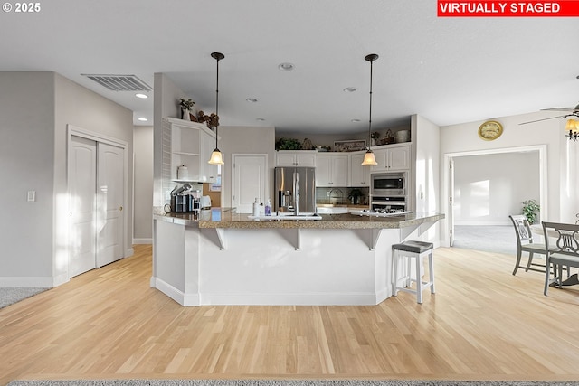 kitchen featuring decorative light fixtures, white cabinetry, a breakfast bar area, backsplash, and stainless steel appliances