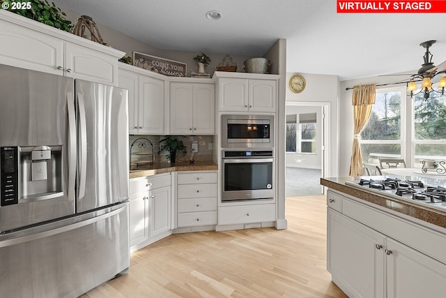 kitchen with ceiling fan, appliances with stainless steel finishes, white cabinetry, tasteful backsplash, and light hardwood / wood-style floors