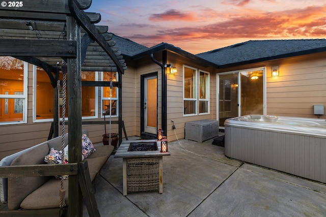 patio terrace at dusk with a hot tub, a pergola, and an outdoor fire pit