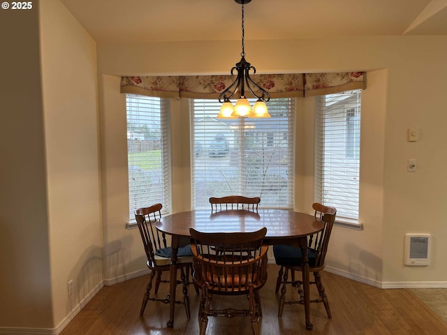 dining space with heating unit, wood-type flooring, and a healthy amount of sunlight