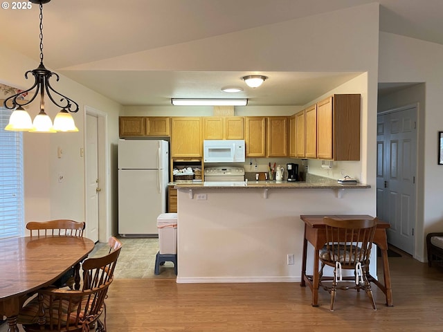 kitchen featuring pendant lighting, white appliances, lofted ceiling, and kitchen peninsula