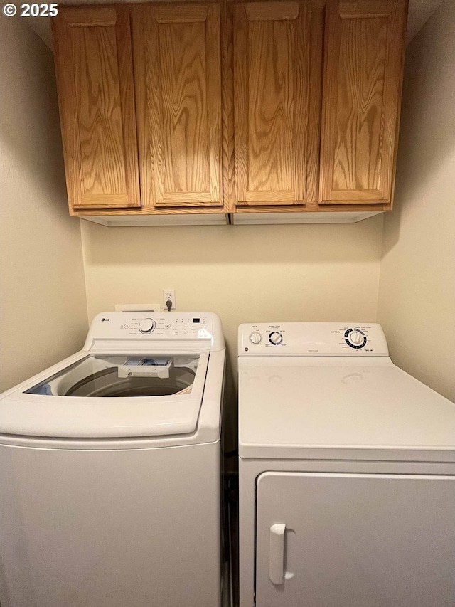 washroom with cabinets and washing machine and dryer