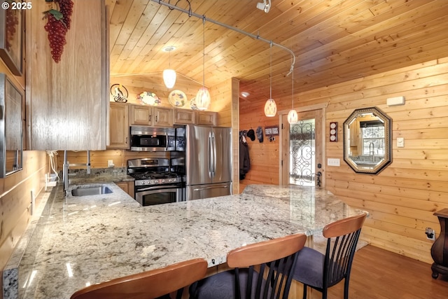 kitchen with appliances with stainless steel finishes, wooden ceiling, lofted ceiling, a sink, and wood walls