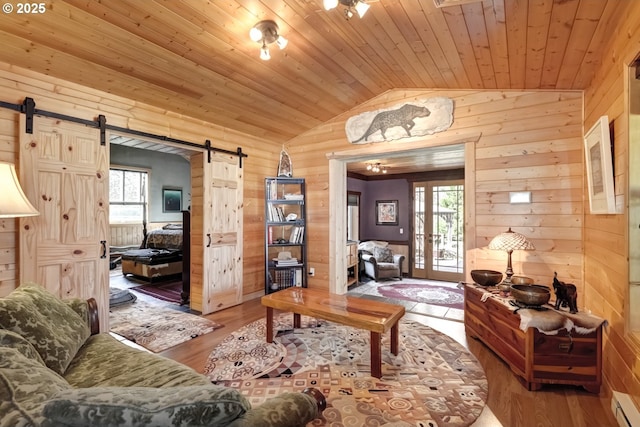 living area featuring vaulted ceiling, a barn door, wooden walls, wooden ceiling, and wood finished floors