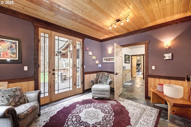 sitting room featuring wooden walls, wainscoting, wood ceiling, and track lighting