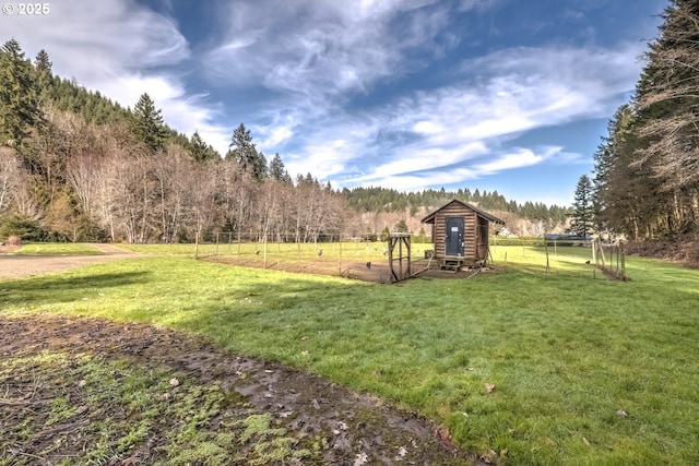 view of yard with a wooded view, a rural view, and fence