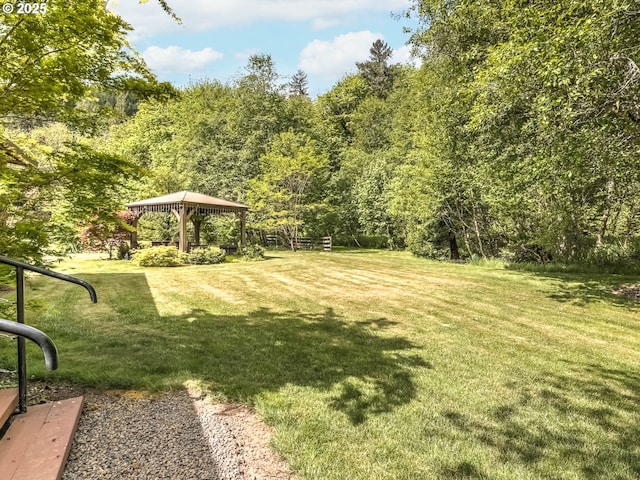 view of green lawn featuring a gazebo and a view of trees