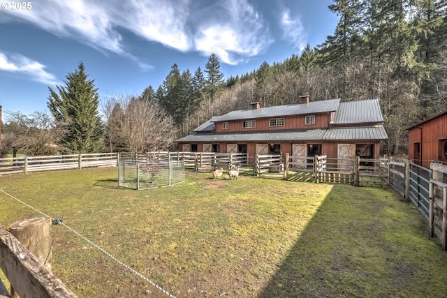 back of house with an outbuilding, an exterior structure, metal roof, and a chimney