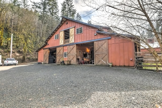 view of barn featuring gravel driveway and fence