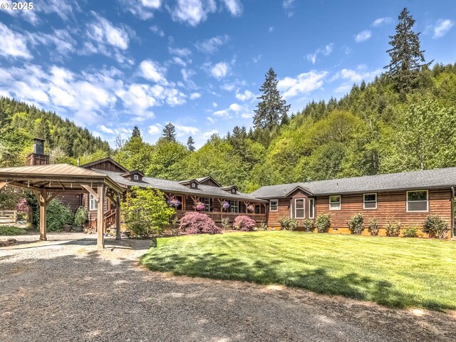 view of front of house with a carport, a front lawn, a gazebo, and a wooded view