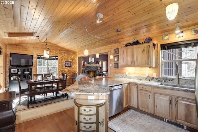 kitchen with visible vents, stainless steel dishwasher, a sink, a stone fireplace, and wooden walls