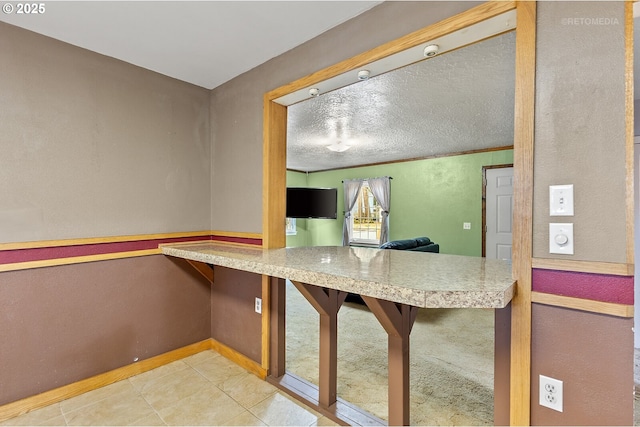 kitchen featuring light tile patterned flooring, crown molding, and built in desk