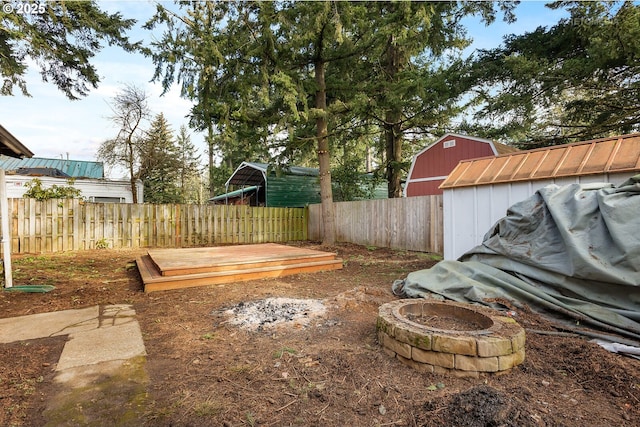 view of yard with a deck, a shed, and an outdoor fire pit