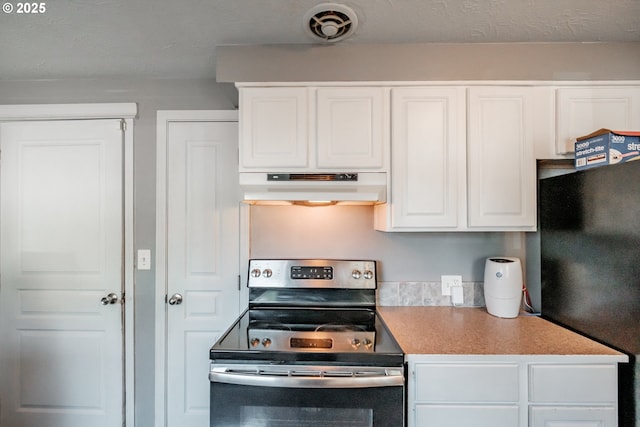 kitchen featuring white cabinetry, black fridge, and electric range