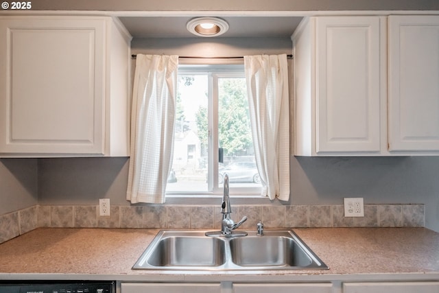 kitchen featuring dishwashing machine, sink, and white cabinets