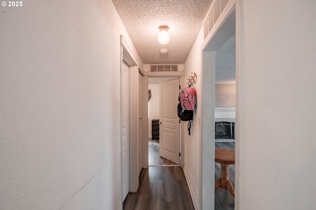 hallway featuring dark hardwood / wood-style floors and a textured ceiling