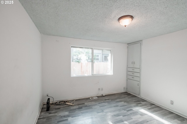 unfurnished room featuring light hardwood / wood-style floors and a textured ceiling