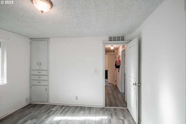 unfurnished bedroom featuring wood-type flooring and a textured ceiling