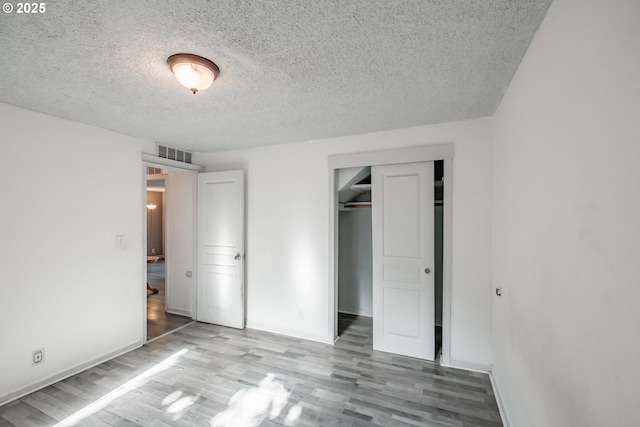 unfurnished bedroom with a closet, light hardwood / wood-style flooring, and a textured ceiling