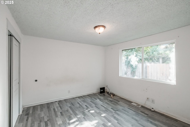 spare room featuring light hardwood / wood-style floors and a textured ceiling