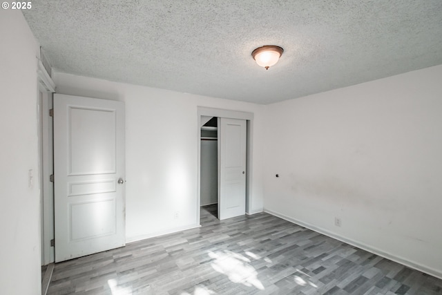 unfurnished bedroom with a closet, light hardwood / wood-style flooring, and a textured ceiling