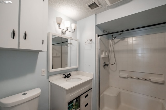 bathroom featuring vanity, tiled shower, a textured ceiling, and toilet