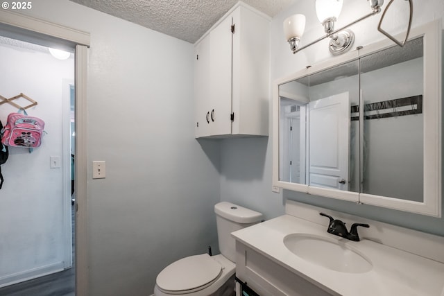 bathroom featuring vanity, toilet, and a textured ceiling