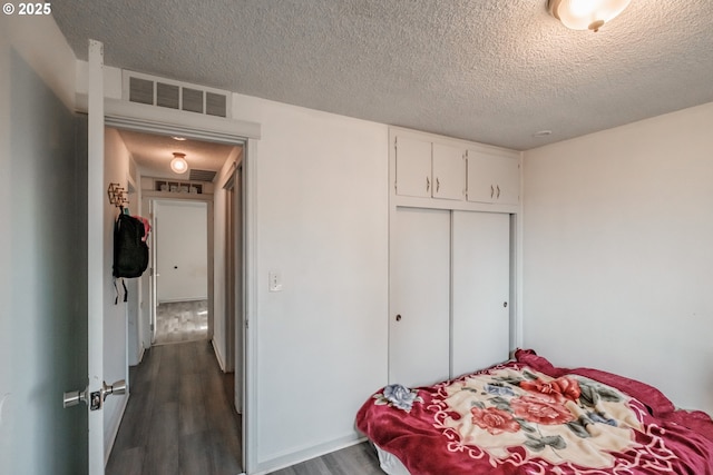 bedroom with a closet, dark hardwood / wood-style flooring, and a textured ceiling