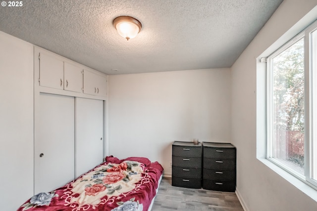 bedroom featuring a textured ceiling, light hardwood / wood-style floors, and a closet